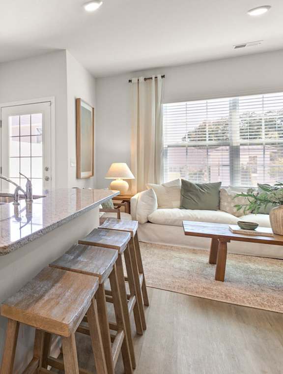 A modern kitchen with a refrigerator, microwave, oven, and a bar area.