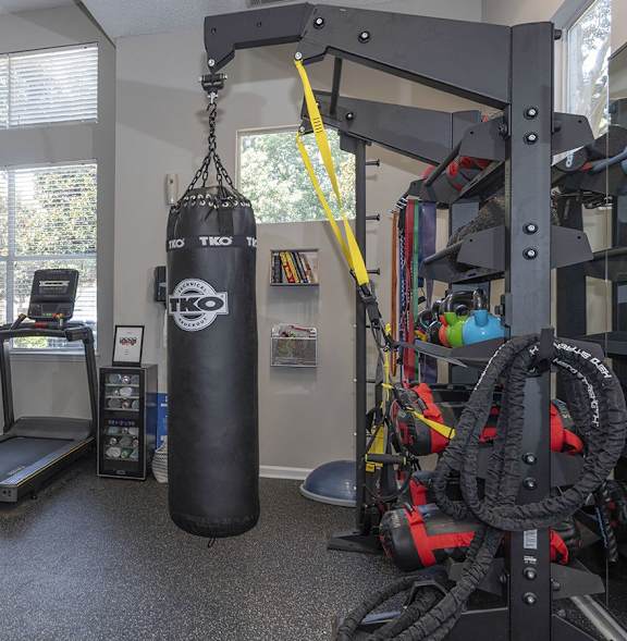A gym with a variety of equipment including a treadmill, weights, and a punching bag.