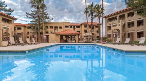 Foothills view of sparkling pool with lounging space and tall trees surrounding