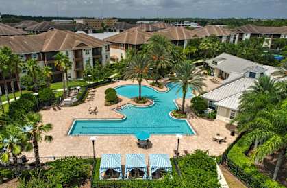 A swimming pool surrounded by palm trees and a resort.