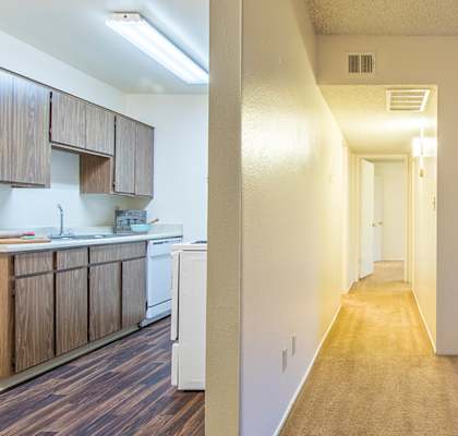 A long hallway with a door at the end and a chair with a blanket on it on the right.