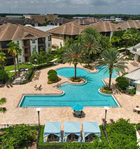 A swimming pool surrounded by palm trees and a resort at Cabana Club - Galleria Club, Jacksonville, Florida