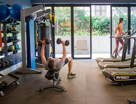A man is working out with dumbbells in a gym.