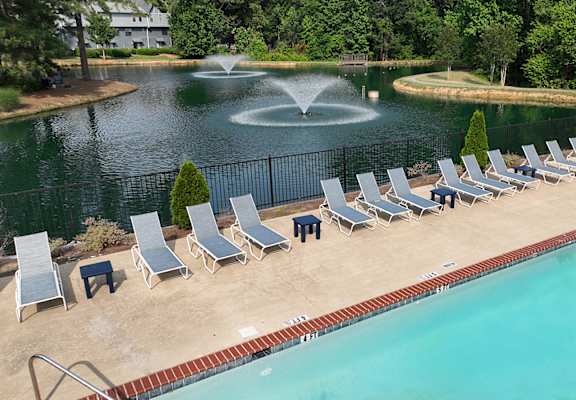a swimming pool with chaise lounge chairs and a fountain in the background