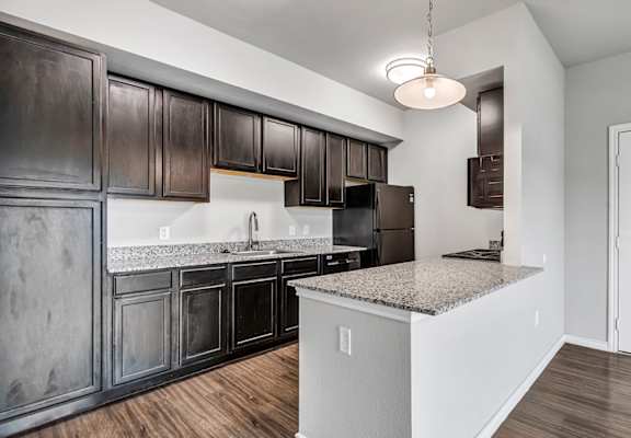 an empty kitchen with dark cabinets and granite counter tops