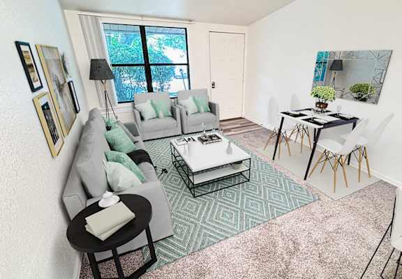 A living room with a grey couch, a black coffee table, and a green rug.