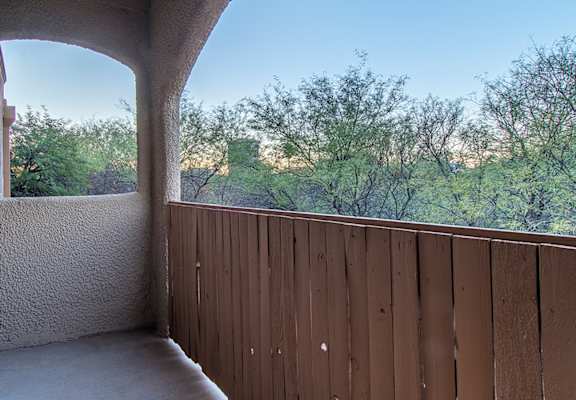 A balcony with a view of trees and sky.