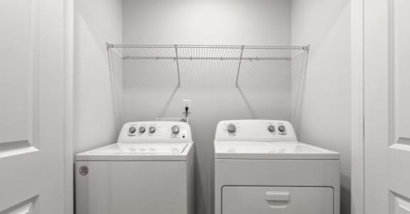 Two white washing machines in a laundry room.