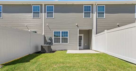 A grey building with a white fence and a green lawn in front.