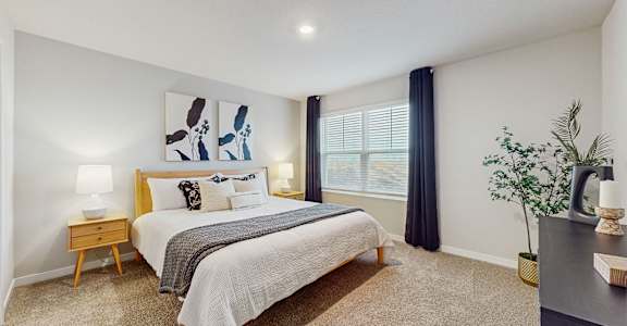 A bedroom with a bed, nightstand, and a painting on the wall.