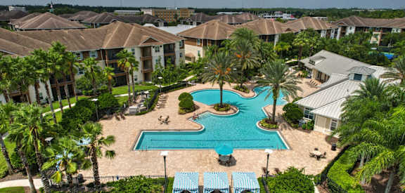 A swimming pool surrounded by palm trees and a resort at Cabana Club Apartments in Jacksonville, 32256