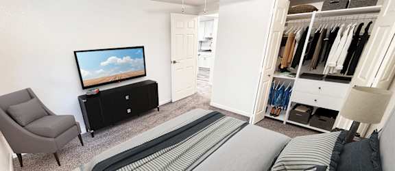 A bedroom with a bed, chair, and a television.