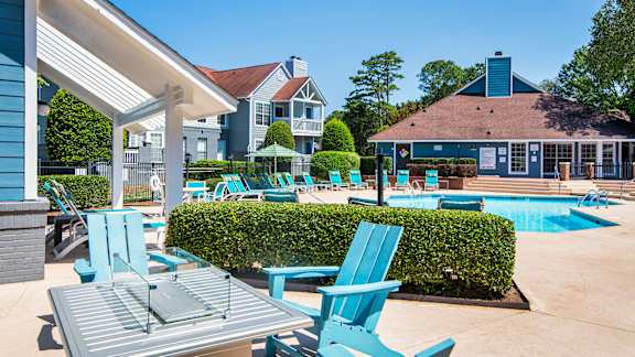 A poolside area with blue chairs and a table.