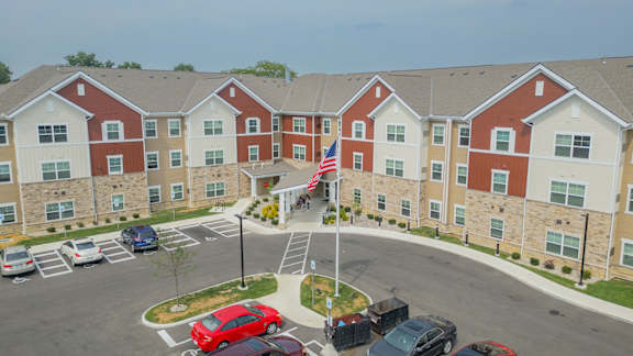 A parking lot in front of a red and white building with a flag on top.