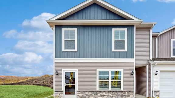 A house with a grey and blue exterior and a white garage door.