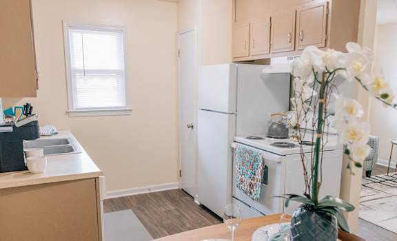 a kitchen and dining room with white appliances and a table with flowers
