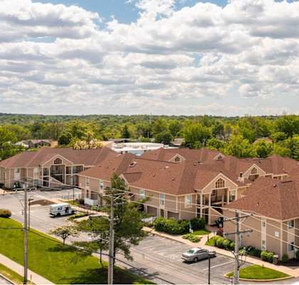 an aerial view of a large building with a parking lot and trees
