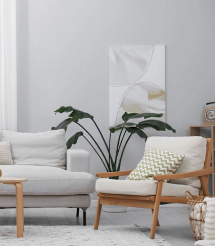 A living room with a white couch, a wooden chair, a wooden table, and a potted plant.