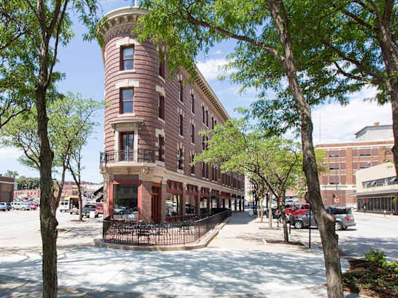 A tall brick building with a round top stands in the middle of a tree-lined street.