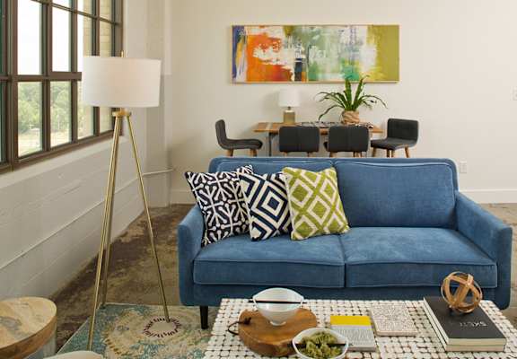 a living room with a blue couch and pillows at Parcels at Concourse, Memphis, TN