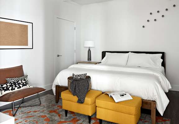 a bedroom with a white bed and a yellow ottoman at Parcels at Concourse, Memphis, 38104