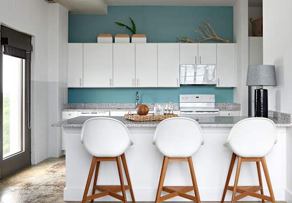 a kitchen with white cabinets and a counter with three white chairs at Parcels at Concourse, Memphis, 38104