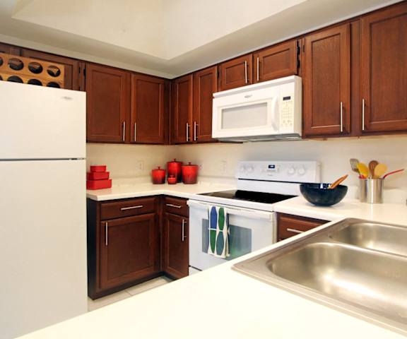 a kitchen with white appliances and wooden cabinets and a sink