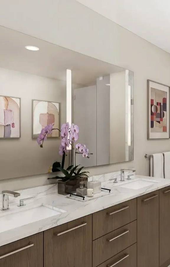 A bathroom with a large mirror, two sinks, and a walk-in shower.