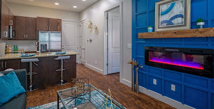 Living Room and Kitchen with Blue Accents and Fireplace in One-Bedroom Apartment