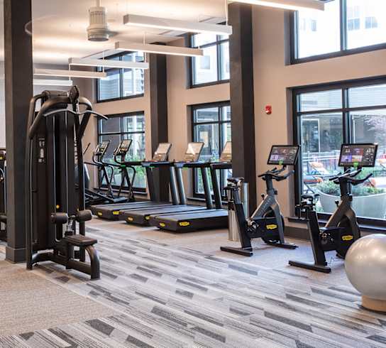 a gym with weights and other exercise equipment in a building with windows at Lyric at Norton Commons Apartments, Prospect, Kentucky