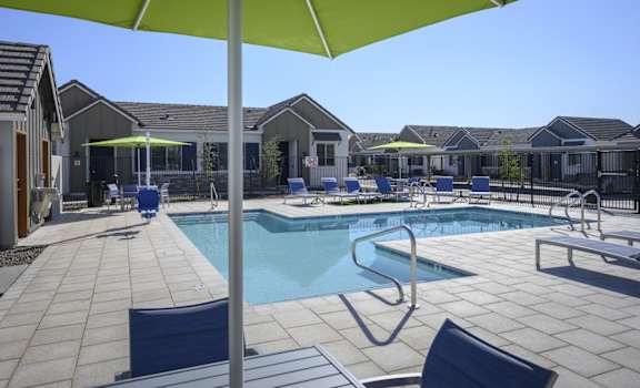 a swimming pool with chairs and umbrellas in front of a house at Village of Chandler, Arizona, 85249