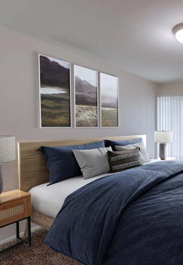 A bedroom with a large bed and a painting on the wall.