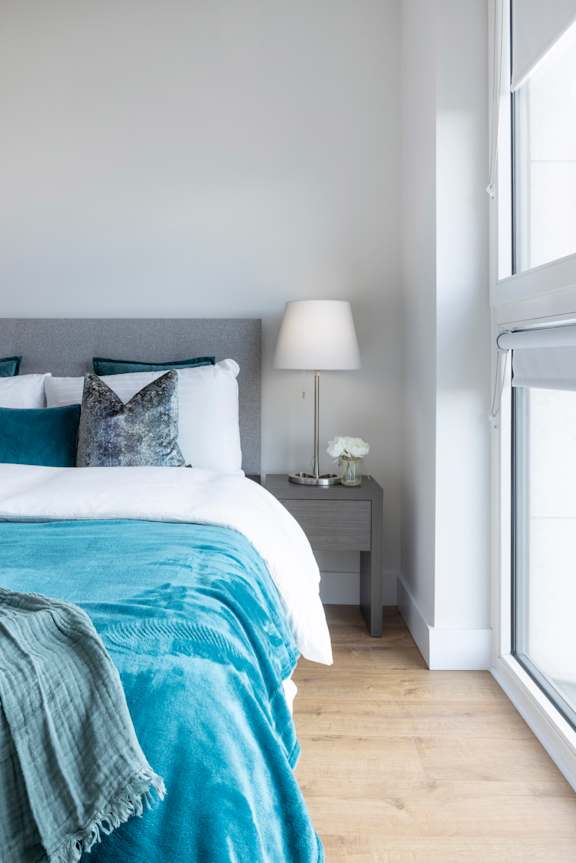 a bedroom with a bed with blue and white sheets and pillows