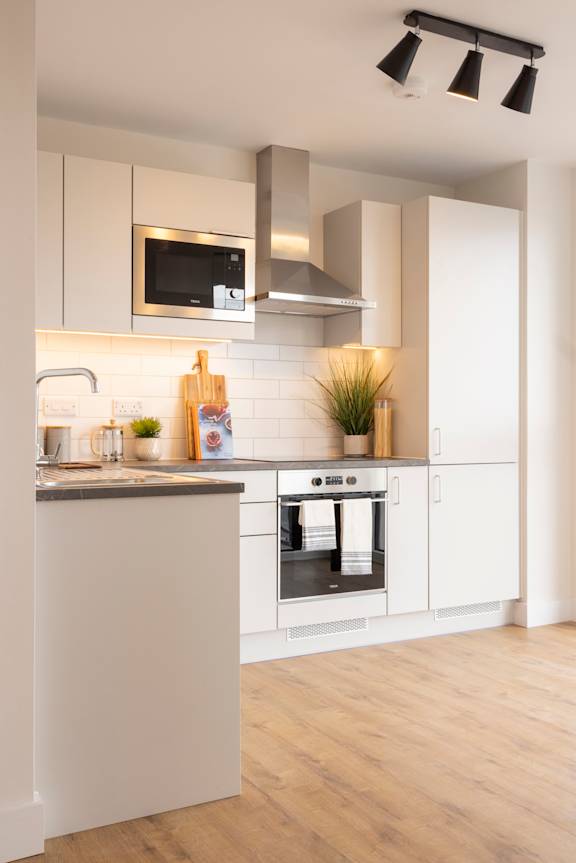 a white kitchen with stainless steel appliances and a wood floor
