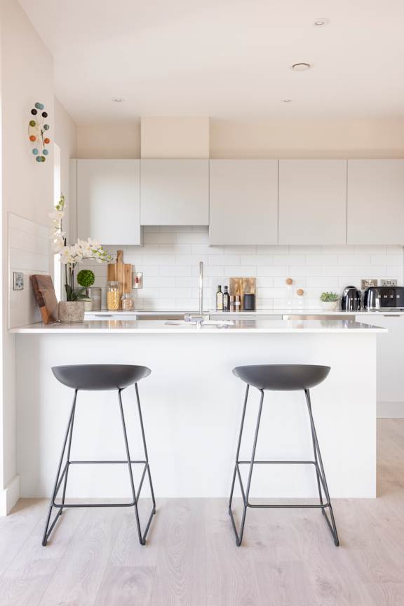 a kitchen with white cabinets and two black bar stools
