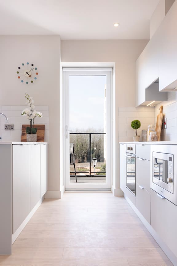 a white kitchen with a door to a patio