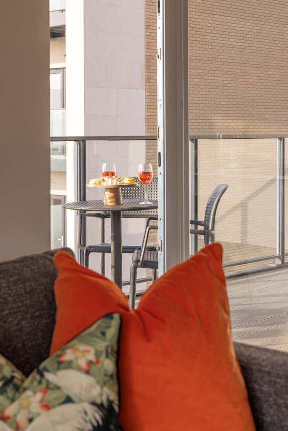 a living room with orange pillows and a table with chairs