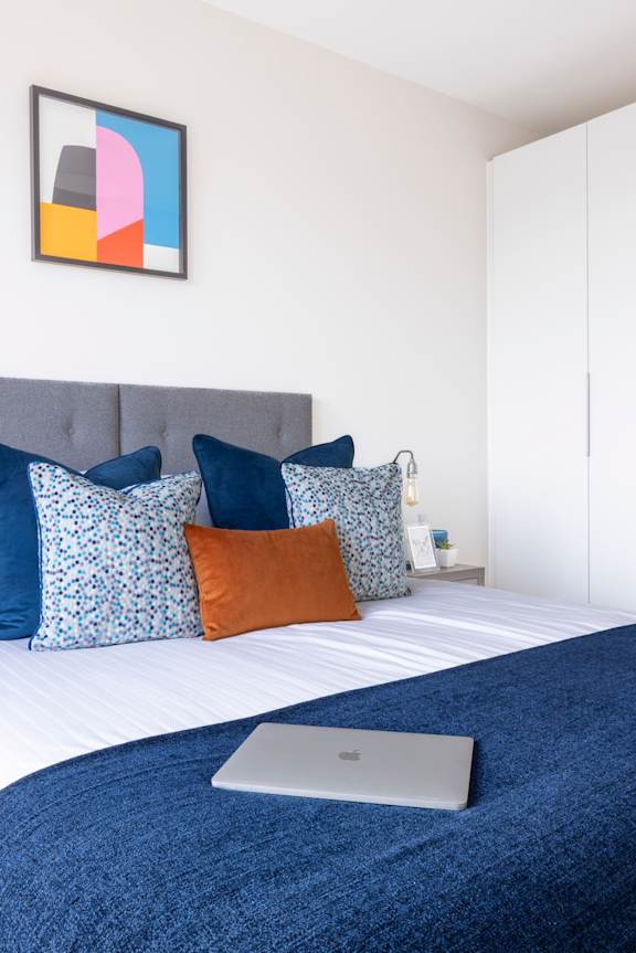 a bed with blue pillows and a laptop on it