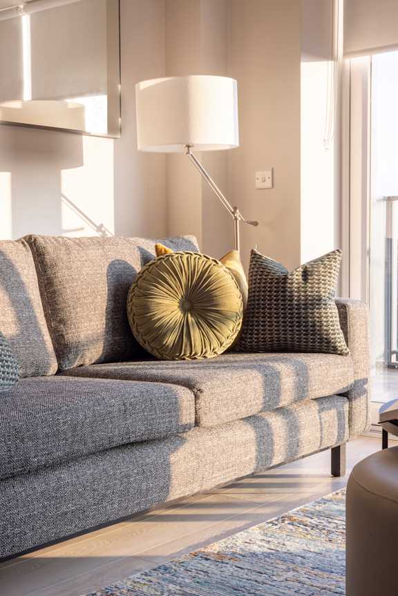 a living room with a couch and pillows and a lamp