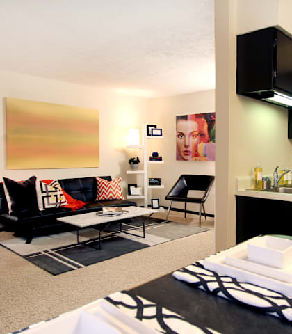 an apartment living room and kitchen with black cabinets and white appliances