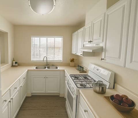 A white kitchen with a sink and a window.