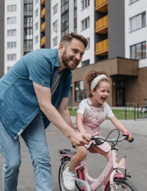 a man helping a little girl ride a bike