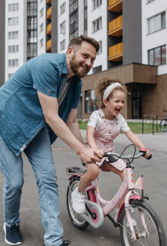 a father helping his daughter ride a bike