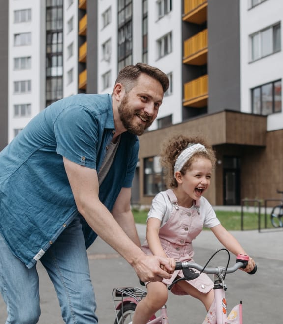 a man helping a little girl ride a bike