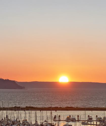 A sunset over a body of water with boats docked in the foreground.