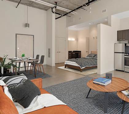A modern living room with a kitchen area in the background. at RiDE at RiNo Apartments, Colorado