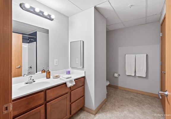 A bathroom with a sink, mirror, and towel rack.