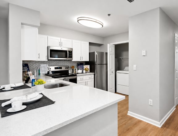 A modern kitchen with white countertops and stainless steel appliances.