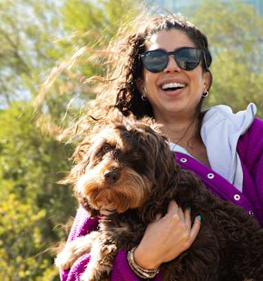 A woman in a purple jacket is holding a dog.