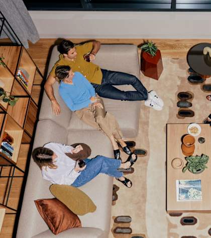 A group of people are sitting and relaxing on a couch in a living room.